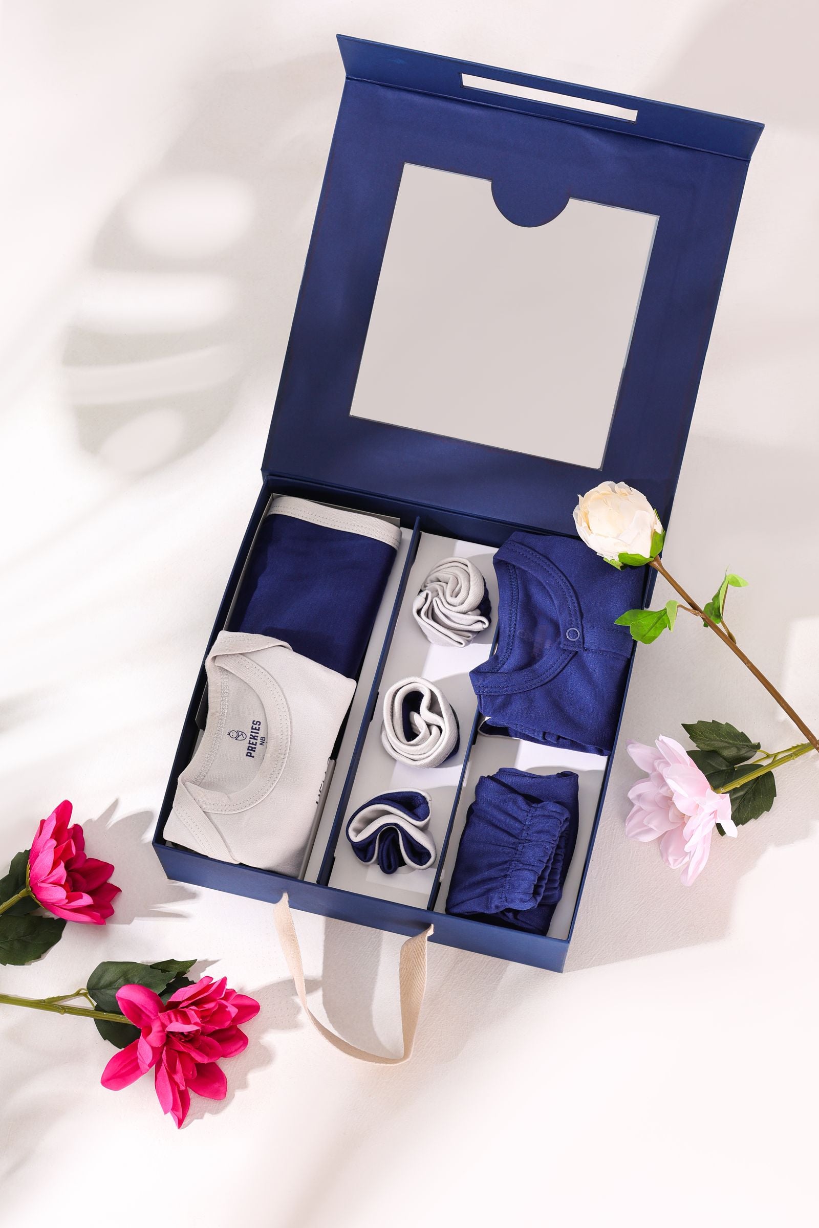 Navy gift box with folded baby clothes, ready for gifting